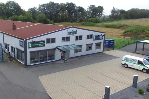 Blick auf das mebod Gebäude mit den beiden Ladesäulen an den Parkflächen